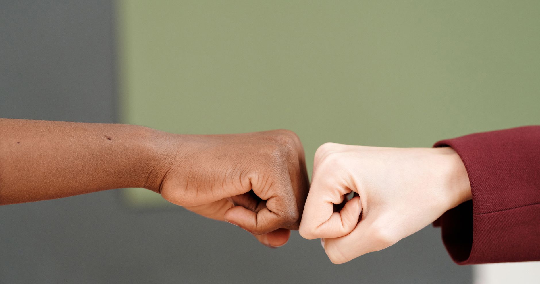 Two people touching fists against a green background